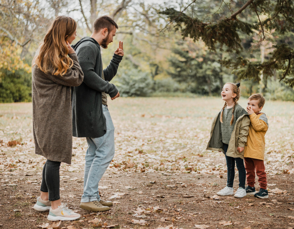 father photographing children while mother watches them smiling in autumn park