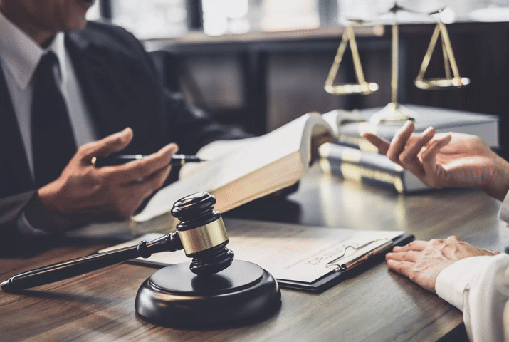lawyers discussing case at desk with gavel documents and scales of justice