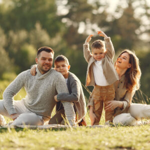 parents with two young children smiling and playing on grassy field outdoors