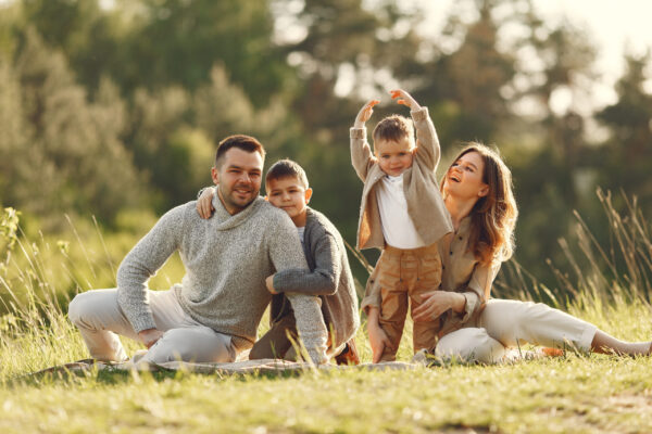 parents with two young children smiling and playing on grassy field outdoors